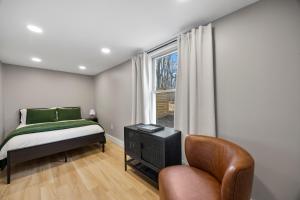 a bedroom with a bed and a chair and a window at Hoosier Hq Sleek 3-bed Near Iu in Bloomington