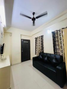 ハイデラバードにあるFlat in Hyderabadのリビングルーム(天井ファン付)の黒いソファ