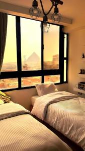 two beds in a bedroom with a large window at Pyramora Inn in Banī Ghālib