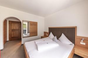 a bedroom with a large white bed with a wooden headboard at Pension Gasthof Haselstaude in San Leonardo in Passiria +38 photos