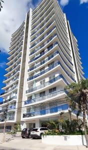 a large white building with cars parked in front of it at APARTAMENTO COMODO EN EQUIPETROL TOTALMENTE AMOBLADO CON 2TVS CON NETFLIX, PISCINA TEMPERADA, GYM, CINE y PARQUEO cerca de Mall Ventura, Cines, restaurants y supermercados in Santa Cruz de la Sierra