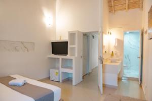a white room with a bed and a sink and a television at Casa Amanzi Cartagena by Bernalo Hotels in Cartagena de Indias