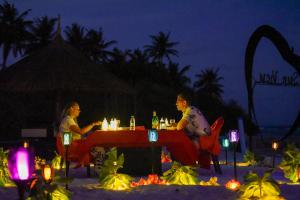 two people sitting at a table on the beach at night at Sunview Residence in Kaashidhoo