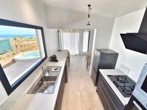 une cuisine avec un évier et une grande fenêtre dans l'établissement Gîte Douceur & Évasion avec Spa Privatif pour 2 - Vue Océan - FR-1-786-71, à Saint-Gilles-les Hauts