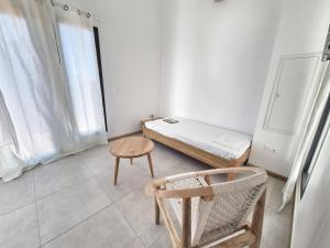 une chambre avec un lit, une table et une chaise dans l'établissement Gîte Douceur & Évasion avec Spa Privatif pour 2 - Vue Océan - FR-1-786-71, à Saint-Gilles-les Hauts