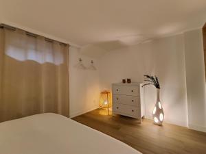 ein Schlafzimmer mit einem Bett, einer Kommode und einer Vase in der Unterkunft Cocon du Tisserand - Centre ville - Cosy et Intimiste in Cholet