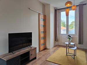 ein Wohnzimmer mit Flachbildfernseher und Fenster in der Unterkunft Cocon du Tisserand - Centre ville - Cosy et Intimiste in Cholet