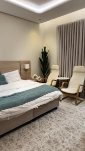 a bedroom with a bed and two chairs and a table at القصواء in Jeddah