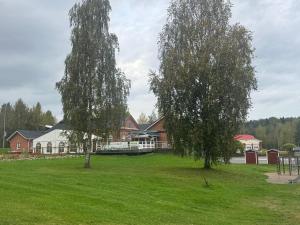 two trees in a field in front of a house at Gasthaus Sahanranta in Kuhmoinen