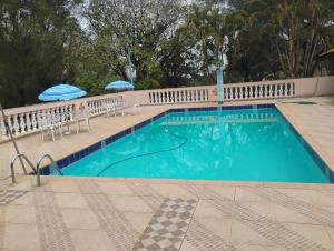 a swimming pool with chairs and umbrellas next to it at Linda Chacara com Piscina próximo a Piracicaba in Piracicaba