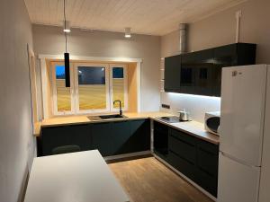 Una cocina con gabinetes negros y un refrigerador blanco. en Ulila Kesk 13, 