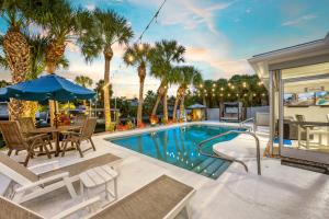 a swimming pool with a table and chairs and palm trees at Siesta Key Waterfront Oasis - Heated Pool, Dock, Walk to Village & Beach in Bailey Hall