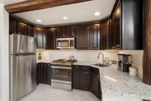a kitchen with wooden cabinets and a stainless steel refrigerator at Aspen Stash Pad with Fireplace, Parking, W/D in Aspen +2 photos