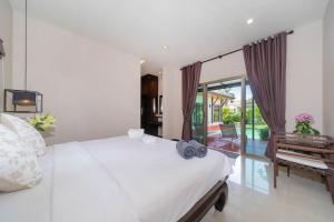 a bedroom with a large white bed and a balcony at 2 bedrooms pool and garden villa Niche 9 Rawai in Ban Nong Chaeng +10 photos