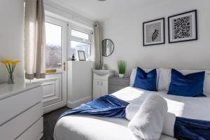 een slaapkamer met een bed met blauwe kussens en een raam bij 3 Bed House - Sleeps 5 - Parking - Wifi in New Brancepeth