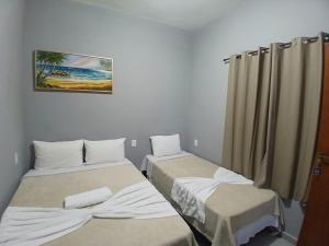 a room with two beds and a painting on the wall at Pousada Milagres de Maria in Aparecida