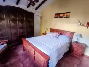 a bedroom with a large bed with a wooden headboard at Los Pinos B&B - Habitación en casa de familia in Cosquín
