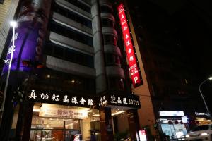 a tall building with neon signs in front of it at Wonderful Hall Hotel in Xinzhuang