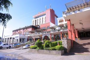 a street with a pink building with bushes in front at Pyramid Hotels & Resorts in Debre Zeyit