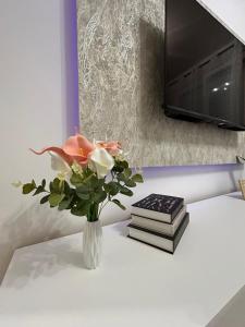 a vase of flowers on a table with books at Apartman Maja in Budžak