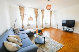 a living room with a blue couch and a tv at KasselRooms Loft - Friedrichsplatz in Kassel