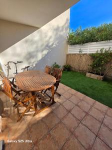 a wooden table and chairs on a patio at Appartement RDC - Grau du Roi in Le Grau-du-Roi