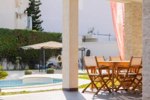 a patio with a table and chairs next to a pool at Villa Oliviera in Akouda
