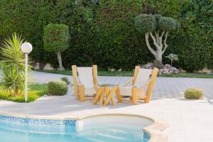 two chairs and a table next to a pool at Villa Oliviera in Akouda