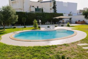 a swimming pool in the yard of a house at Villa Oliviera in Akouda