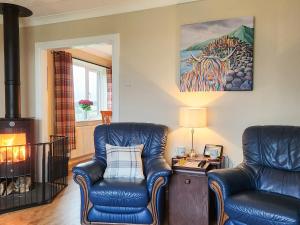 two blue leather chairs in a living room with a fireplace at Seven Seasons in Caldercruix