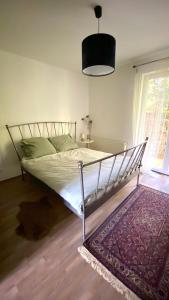 a bed in a bedroom with a rug and a window at Rózsa Vendégház INGYENES PARKOLÁSSAL in Nagykovácsi