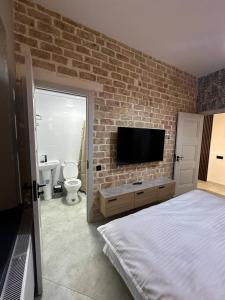 a bedroom with a brick wall with a bed and a tv at Begzod's Loft House in Samarkand
