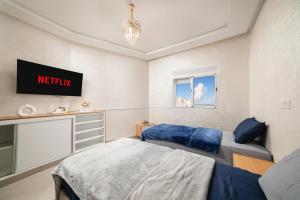 a bedroom with two beds and a tv on the wall at Jaws Wave ESSAOUIRA in Al Ghar