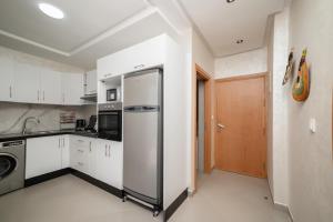 a kitchen with white cabinets and a refrigerator at Jaws Wave ESSAOUIRA in Al Ghar