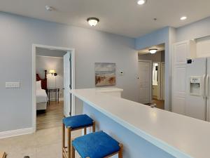 a kitchen with a white counter and two blue stools at The Village #514 in Blue Mountain Beach