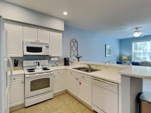 a kitchen with white appliances and blue walls at The Village #514 in Blue Mountain Beach +23 photos