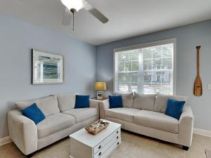 a living room with a white couch and blue pillows at The Village #514 in Blue Mountain Beach