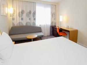 a hotel room with a bed and a couch and a desk at Novotel Toulouse Purpan Aéroport in Toulouse +57 photos