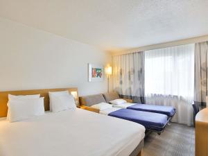 a hotel room with two beds and a window at Novotel Toulouse Purpan Aéroport in Toulouse