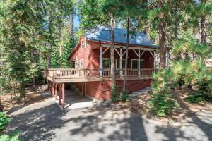 a red house with a deck in the woods at Dogwood Star Rustic-chic Cabin In Shaver Lake in Shaver Lake