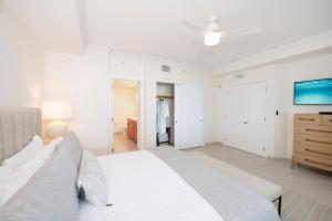 Un dormitorio blanco con una cama y un ventilador de techo. en Beachcomber 21, en George Town