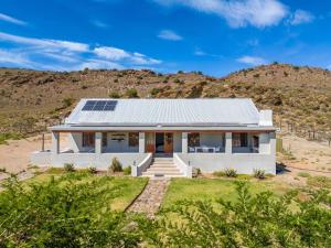 a white house with solar panels on the roof at Aardvark Bioreserve in Ladismith