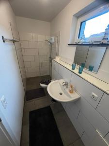 a white bathroom with a sink and a window at Ferienwohnung bei Wessels in Schloß Holte-Stukenbrock +2 photos
