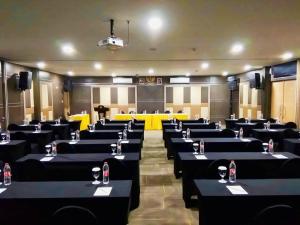 a conference room with black tables with wine glasses on them at Green Red Hotel Syariah Jombang in Jombang
