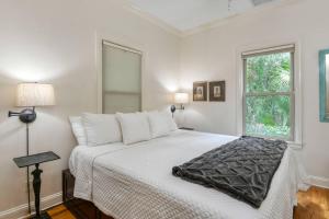 a bedroom with a white bed with a window at Little Blue Cottage in St. Augustine