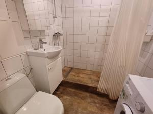 a white bathroom with a toilet and a sink at Two room apartment near buss station and border in Narva