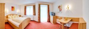 a bedroom with a bed and a desk and a tv at Appartements Michaela in Neustift im Stubaital