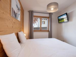 ein Schlafzimmer mit einem weißen Bett und einem Fernseher in der Unterkunft Appartement charmant 4 pers, piste proche, parking, Les Saisies - FR-1-809-13 in Les Saisies