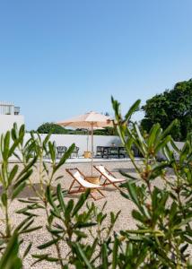 un paio di sedie e un ombrellone in spiaggia di Coastal Garden Suite - Kismet Boutique B&B a Serra do Bouro
