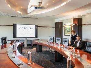 two people standing in a conference room with a screen at Mercure Paris CDG Airport & Convention in Roissy-en-France